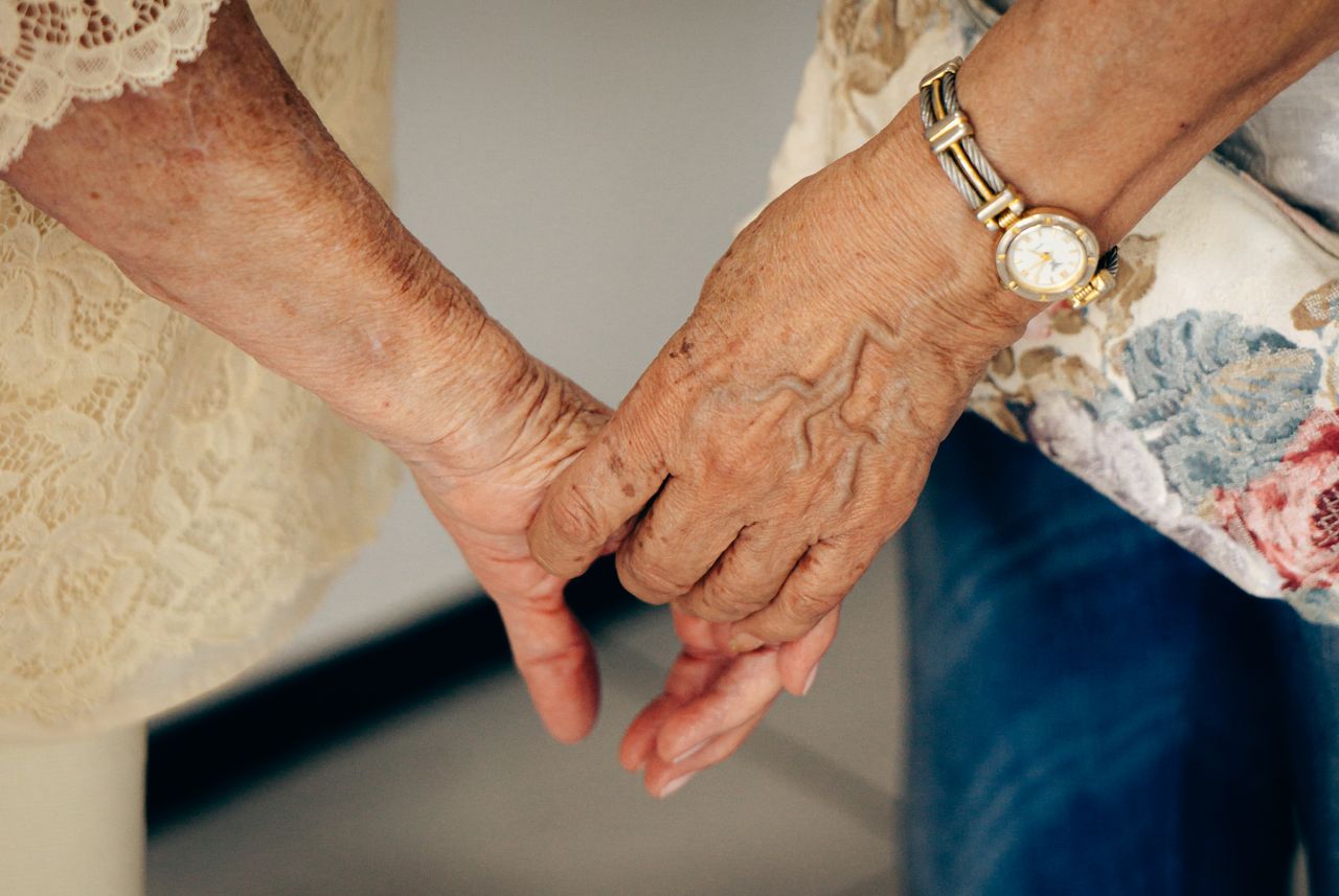 heros-img Close-up of elderly hands holding each other, symbolizing care and companionship.